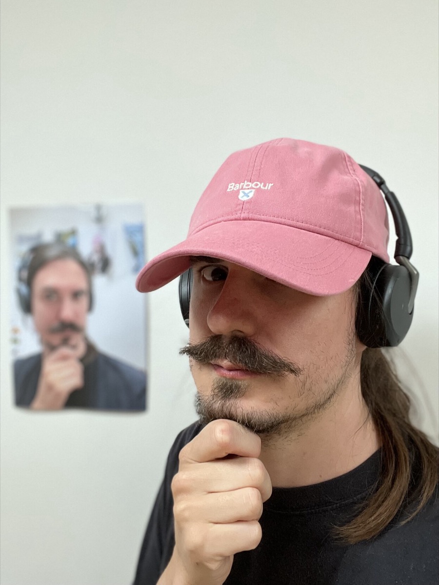 Phil standing in front of a wall bearing a large printout of his own face.